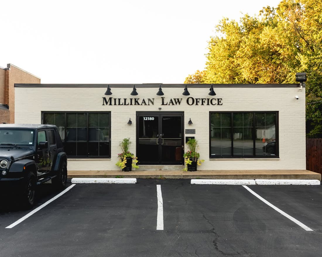 The Millikan Law Office building on Old Big Bend Road: white brick, the firm’s name in black letters under five lamps, and parking out front
